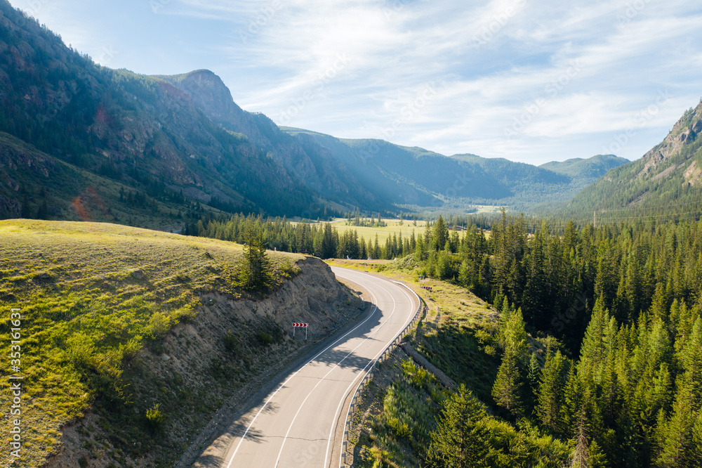 Φωτογραφία Aerial view of scenic road in green mountain valley with pines on a sunny summer morning