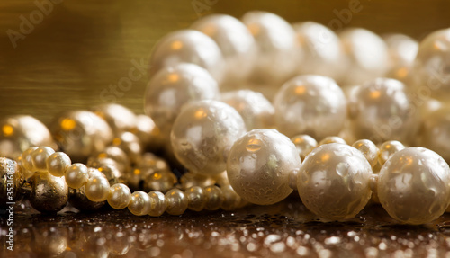 White pearls, female gift jewelry necklace on gold background, closeup