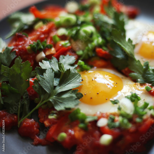 Shakshuka - fried eggs with tomatoes, onion, pepper and spices on a plate