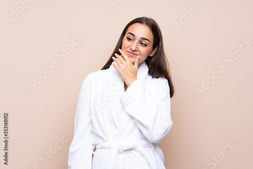 Young girl in a bathrobe over isolated background thinking an idea