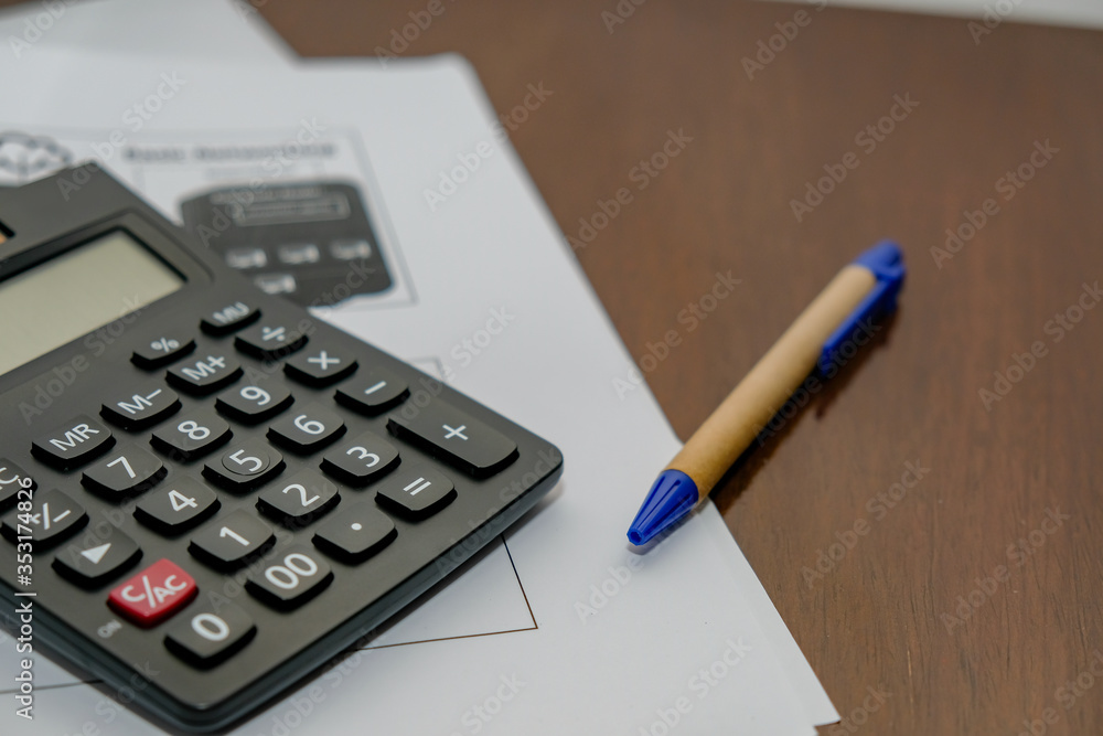 Calculator Documents with pen Resting on a wooden table Calculator Documents with pen Resting on a wooden table