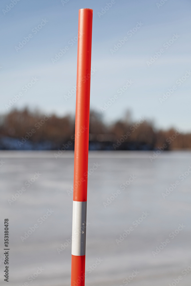 an orange stick with reflective material to mark the beginning and end of the road when it is winter an orange stick with reflective material to mark the beginning and end of the road when it is winter