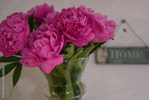 Bouquet of pink peonies glass vase with a sign hime on the wall