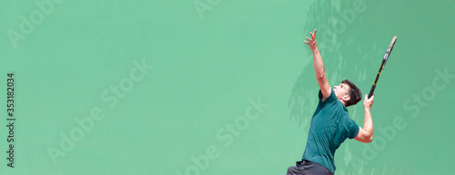Young man tennis player playing tennis on the court.Tennis player serve the ball during a match. First hit. Start of the match. Light green background. Panoramic view. Banner size. Copy space for text © Elena