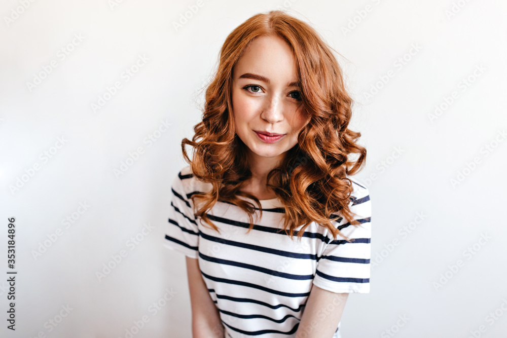 Fascinating white woman with red hair looking to camera with interested smile. Indoor shot of glad european model with wavy hairstyle. Fascinating white woman with red hair looking to camera with interested smile. Indoor shot of glad european model with wavy hairstyle.