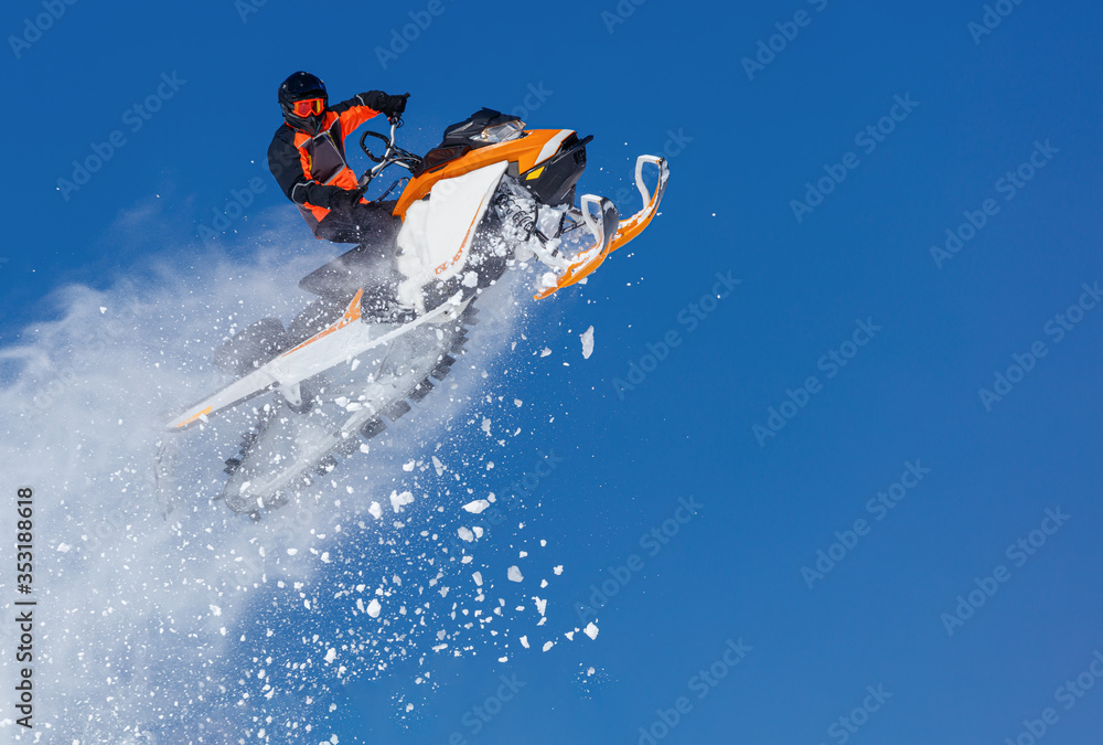 Extreme sport race snowmobiles. Snowmobile in high jump above track. Sportsman on snowmobile. Winter competition, sunny day. Trick against blue sky. Snow motor sports Copy space. Extreme sport race snowmobiles. Snowmobile in high jump above track. Sportsman on snowmobile. Winter competition, sunny day. Trick against blue sky. Snow motor sports Copy space.