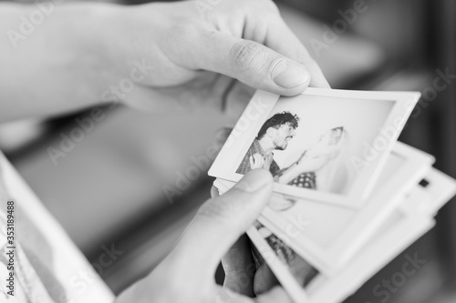 Close-up of man holding in the hand printed photos with picture of young couple.