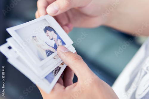 Close-up of man holding in the hand printed photos with picture of young couple.
