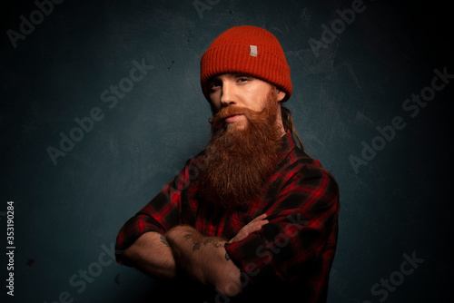 Red bearded man with orange hat and plaid shirt on cyan background © Grigoriy