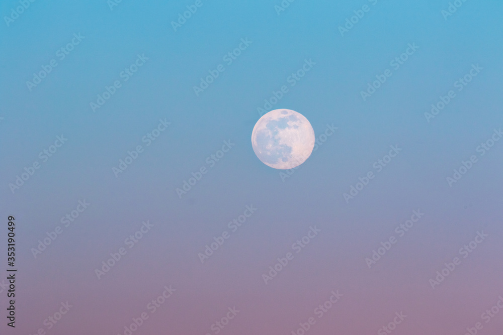 Full moon rising during spring evening with blue and pink sky. Full moon rising during spring evening with blue and pink sky.