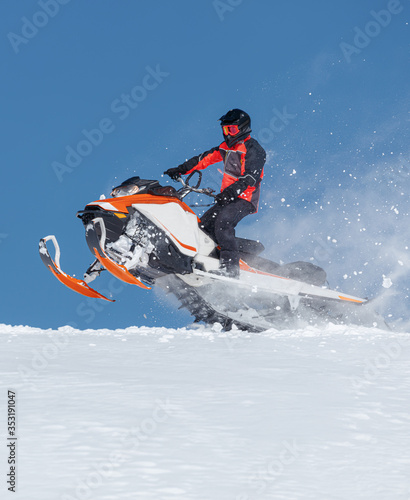 Snowmobile Jump. Extreme Snowmobile Ride & Racing. a bright suit and a snow motorcycle. Winter Recreation. high resolution and photo quality