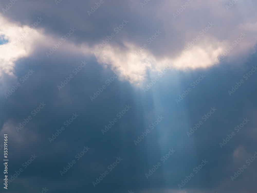 Fototapeta premium The sun's rays create a cone of light emanating from dense dark clouds