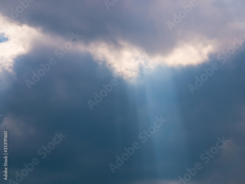 The sun's rays create a cone of light emanating from dense dark clouds