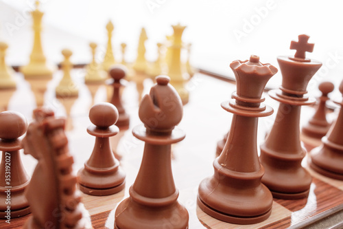 Image of chess pieces on a chessboard. World Chess Day. International Chess Day. July 20. Side view. Closeup. White background. Focus on the front figures photo