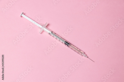 Parts of medical syringe isolated on pink background. Needle, syringe barrel with piston, scale dosage.