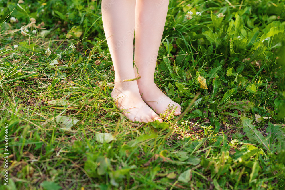 Little child's barefoot standing on a green grass in the park. Barefoot on grass.