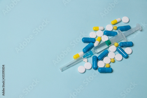 Medical syringe and pills on a dark blue background, health and vaccination concept.