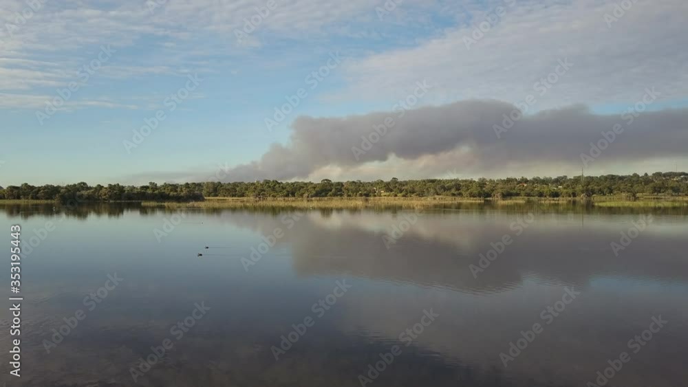 Aerial view above lake of bushfire outside of Perth, Western Australia, with smoke and blue sky over horizon. Aerial view above lake of bushfire outside of Perth, Western Australia, with smoke and blue sky over horizon.