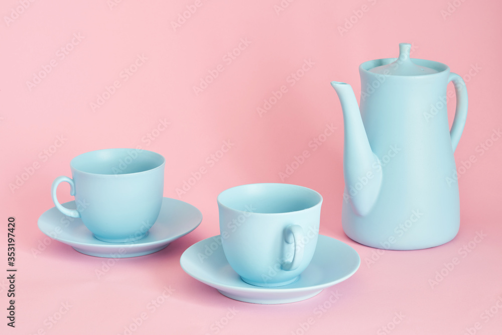 minimalism concept with light pastel colored blue cups teapot and plate on pink background. minimalism concept with light pastel colored blue cups teapot and plate on pink background.