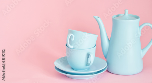 minimalism concept with light pastel colored blue cups teapot and plate on pink background.