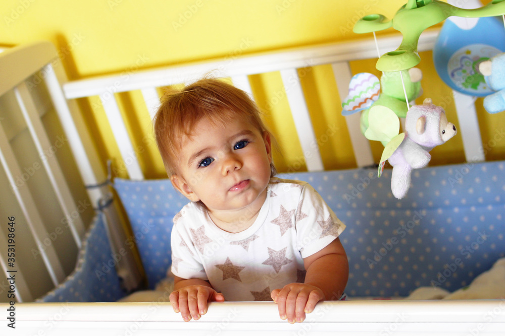 Cute one year old girl with blue eyes and blond hair just woke up in the morning in her bed. Cute one year old girl with blue eyes and blond hair just woke up in the morning in her bed.