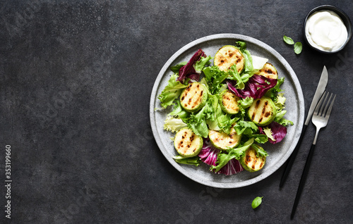 Mix salad with grilled zucchini and sauce on a black background.Top view with copy space.