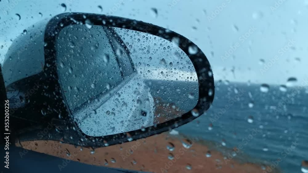 Raindrops run down the glass and mirror of the car. Hide from the rain in the car. Grey landscape through the window. Rainy day. Heavy rain outside the window. Bad weather. Raindrops run down the glass and mirror of the car. Hide from the rain in the car. Grey landscape through the window. Rainy day. Heavy rain outside the window. Bad weather.