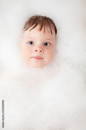 Baby in bath tub bathroom with soap swim in water