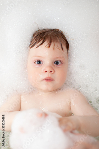 Baby in bath tub bathroom with soap swim in water