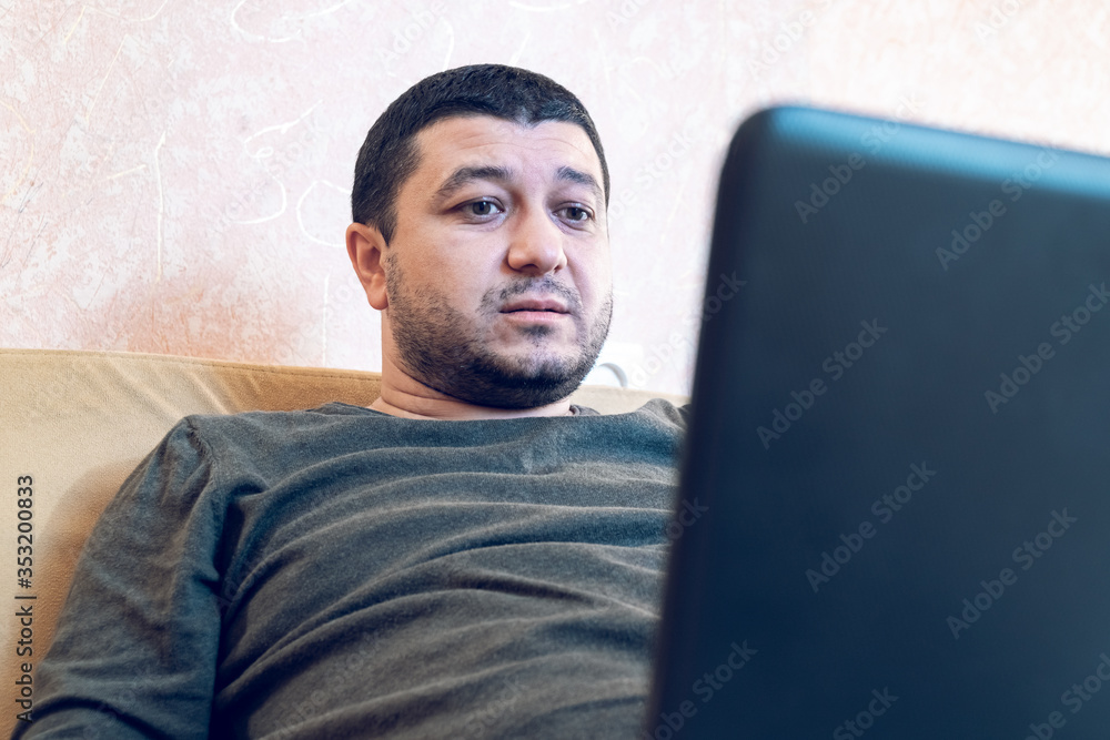 Young man sitting on a sofa with a laptop at home Young man sitting on a sofa with a laptop at home