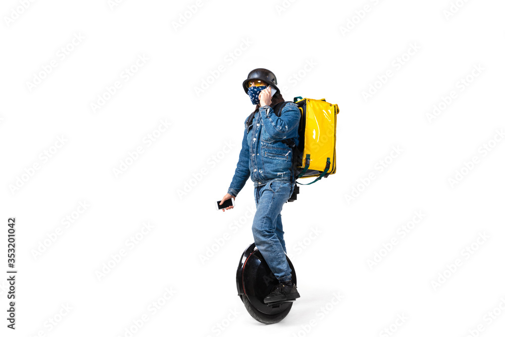 Too much orders. Contacless delivery service during quarantine. Man delivers food wearing gloves and face mask isolated on white. Taking pizza on unicycle isolated on white background. Safety. Too much orders. Contacless delivery service during quarantine. Man delivers food wearing gloves and face mask isolated on white. Taking pizza on unicycle isolated on white background. Safety.