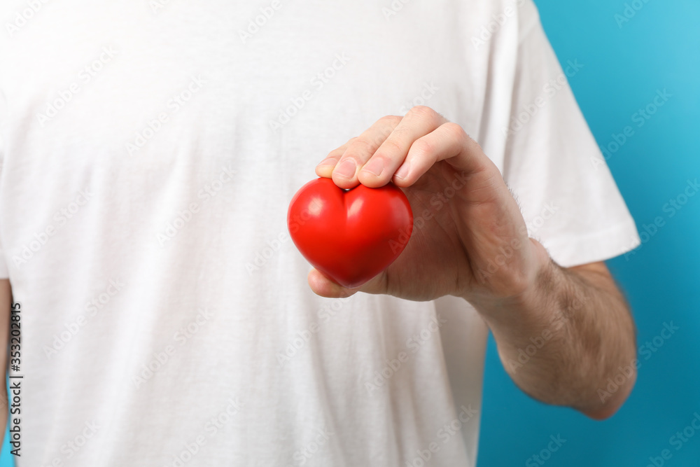 Man holds heart on blue background, close up. Health care, organ donation Man holds heart on blue background, close up. Health care, organ donation