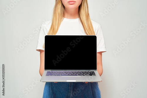 Pretty woman in a white t-shirt and jeans holds a laptop. White background. Layout for a laptop. Black screen