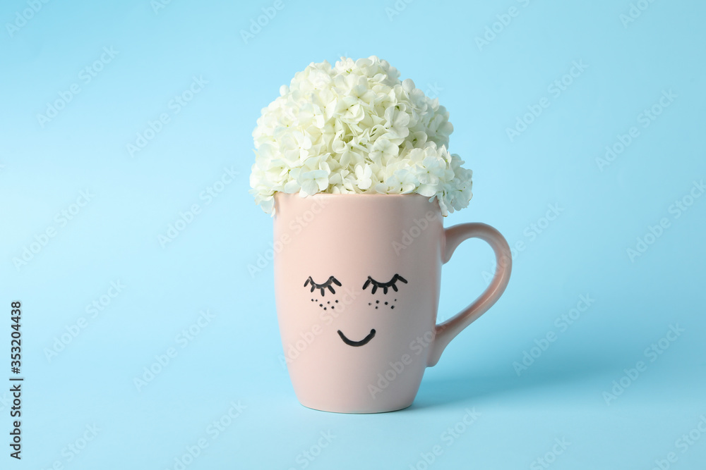 Cup with hydrangea flowers on blue background. Spring plant