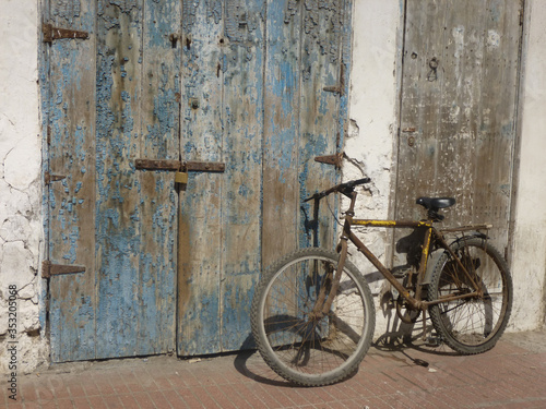 Bicycle leaning against weathered wooden door with lock