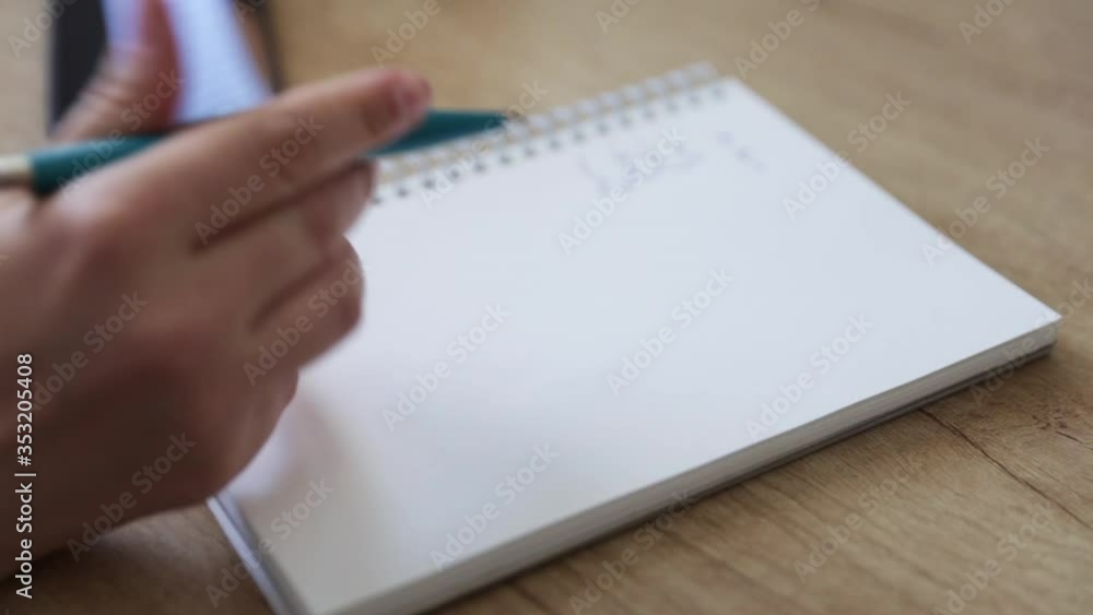 Close-up woman's hand knocks nervously on the notebook with pen and starts writing on bright background. Person thinks at the cafe. Girl is considering a solution to the problem. Close-up woman's hand knocks nervously on the notebook with pen and starts writing on bright background. Person thinks at the cafe. Girl is considering a solution to the problem.