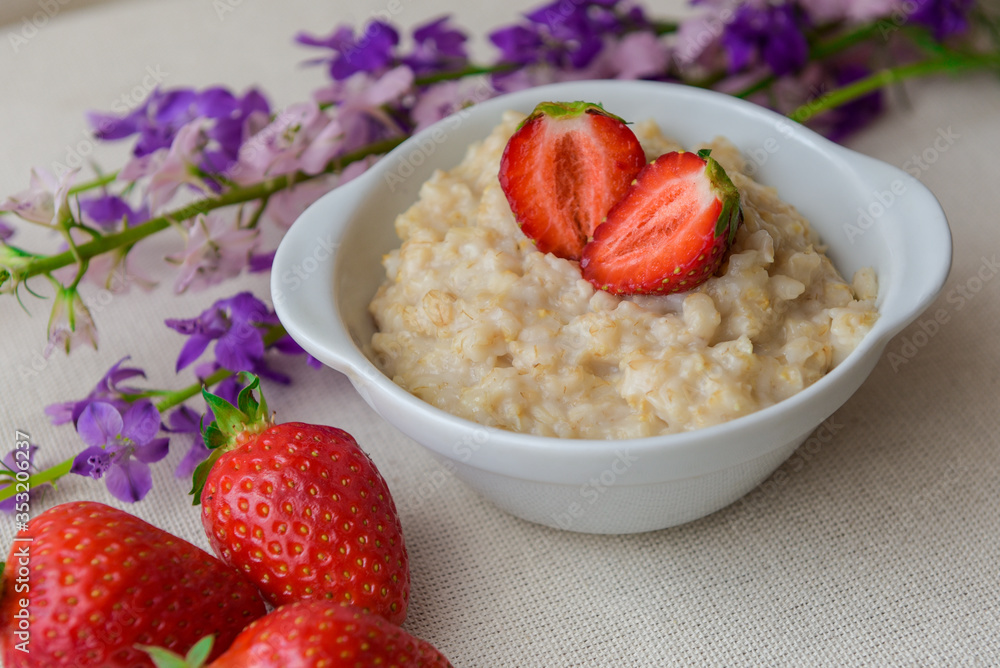 Oatmeal with strawberries in a white bowl. Healthy breakfast, vegetarian lifestyle concept Oatmeal with strawberries in a white bowl. Healthy breakfast, vegetarian lifestyle concept
