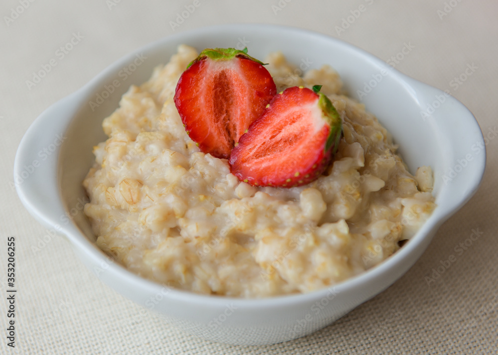 Oatmeal with strawberries in a white bowl. Healthy breakfast with oatmeal and fresh organic berries. Hot and healthy breakfast. Dietary nutrition. Top view, close up Oatmeal with strawberries in a white bowl. Healthy breakfast with oatmeal and fresh organic berries. Hot and healthy breakfast. Dietary nutrition. Top view, close up