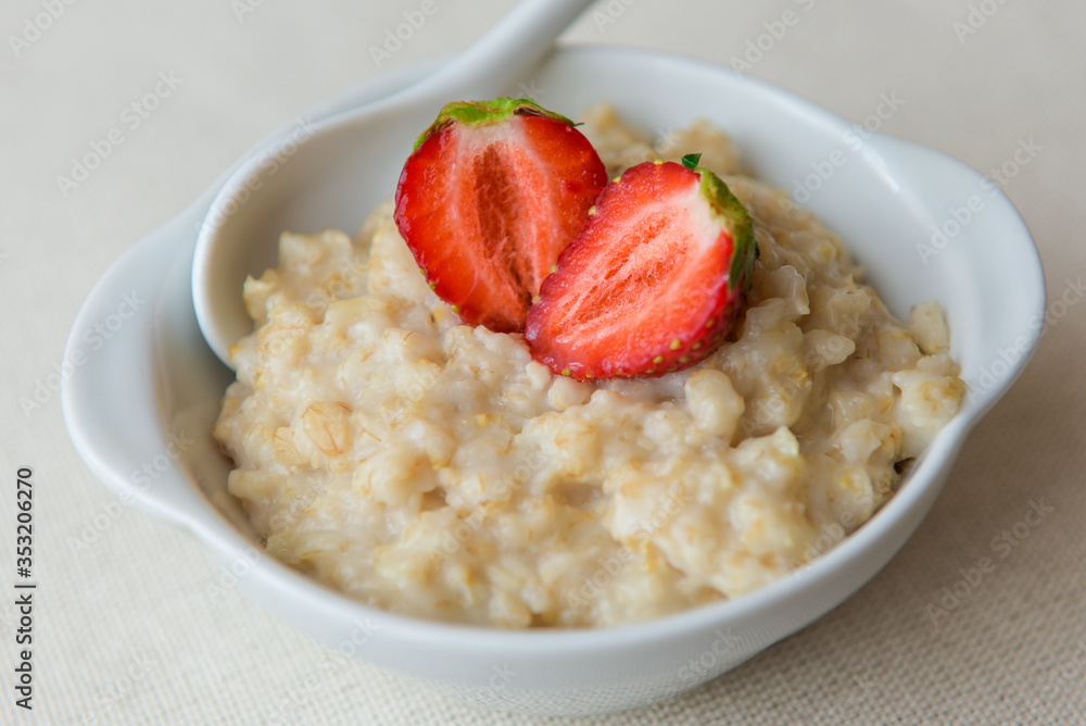 Oatmeal with strawberries in a white bowl. Healthy breakfast with oatmeal and fresh organic berries. Hot and healthy breakfast. Dietary nutrition. Top view, close up Oatmeal with strawberries in a white bowl. Healthy breakfast with oatmeal and fresh organic berries. Hot and healthy breakfast. Dietary nutrition. Top view, close up