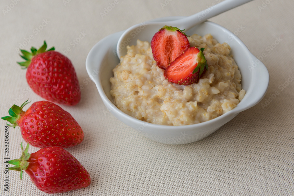 Oatmeal with strawberries in a white ceramic plate with a spoon. Useful work. Strawberry on oatmeal. Close-up
Oatmeal with strawberries in a white ceramic plate with a spoon. Useful work. Strawberry on oatmeal. Close-up