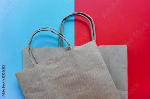 Top view of empty line of craft paper bags on blue and red background. Flat lay on contrast background, zero waste. Garbage recycling. Template or Mockup for designers. stop plastic pollution