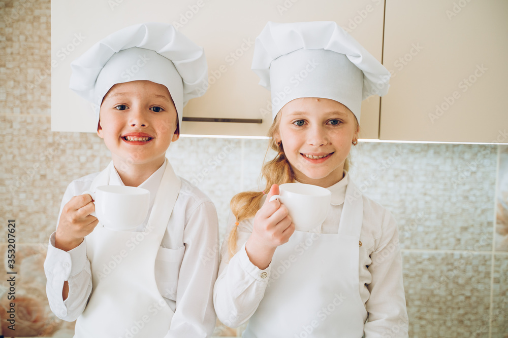 kids cooks in modern kitchen in white bathrobes and hats kids cooks in modern kitchen in white bathrobes and hats