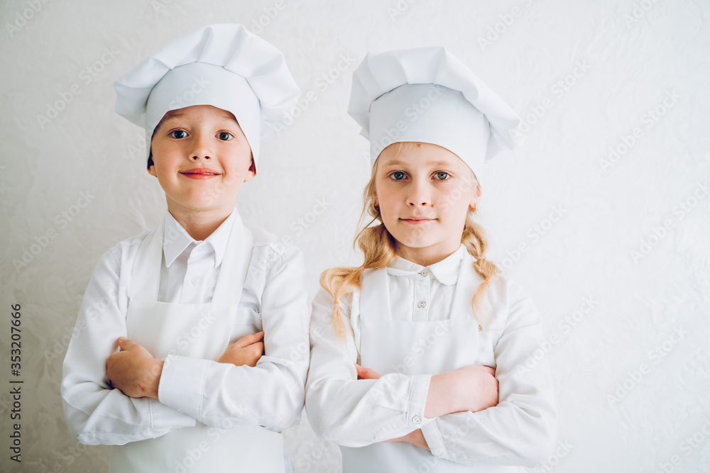 kids cooks in modern kitchen in white bathrobes and hats kids cooks in modern kitchen in white bathrobes and hats