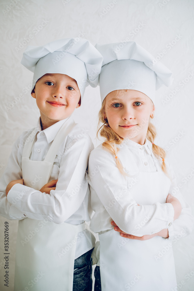 kids cooks in modern kitchen in white bathrobes and hats kids cooks in modern kitchen in white bathrobes and hats