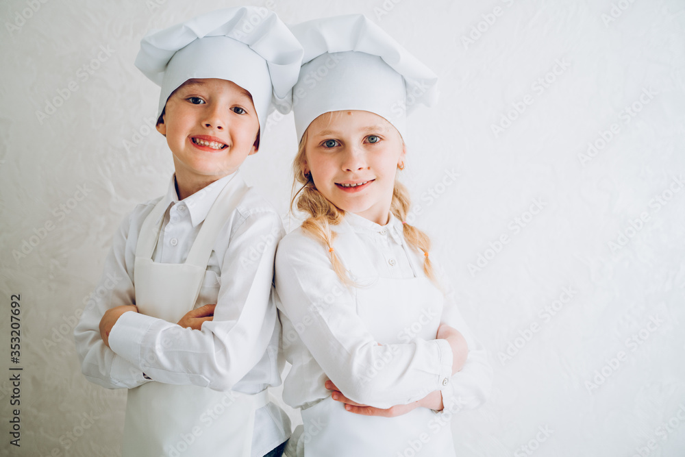 kids cooks in modern kitchen in white bathrobes and hats kids cooks in modern kitchen in white bathrobes and hats