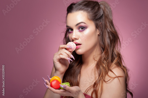 Young sexy woman eating color macarons candies