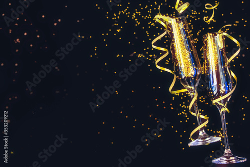 Confetti in the shape of stars poured out glasses of champagne on the black background