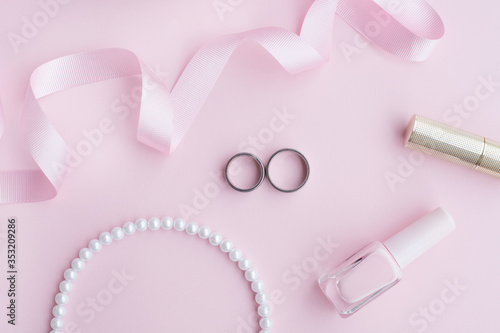 Wedding jewelry rings in the composition with the bride's bouquet on a pink background. Concept photo for a wedding