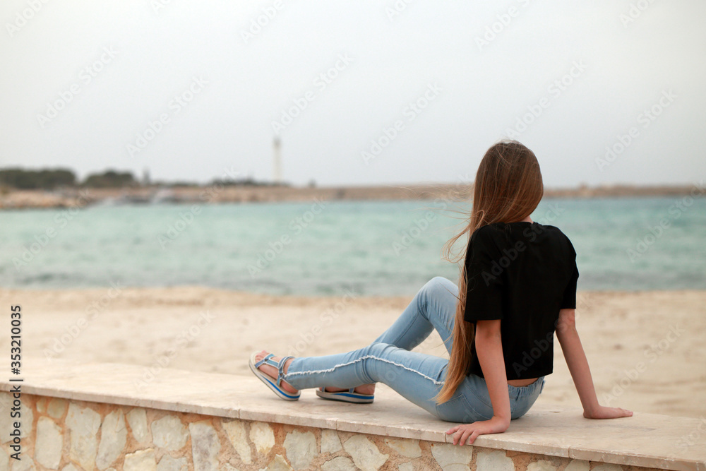 Seduta sul muretto guarda verso il mare