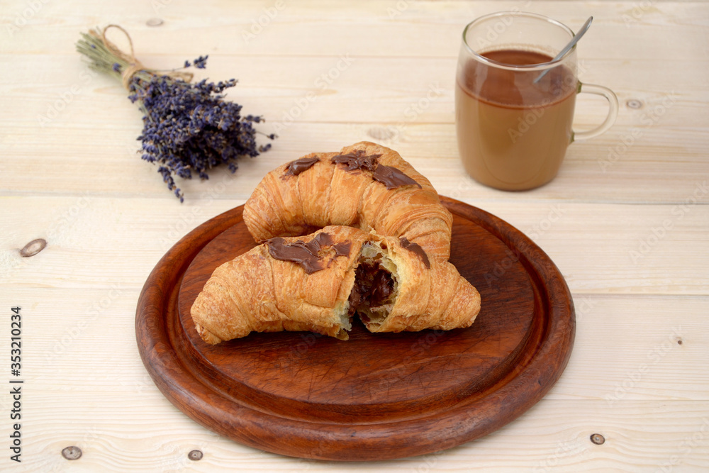 croissants with chocolate and a cup of coffee with milk on a wooden table
